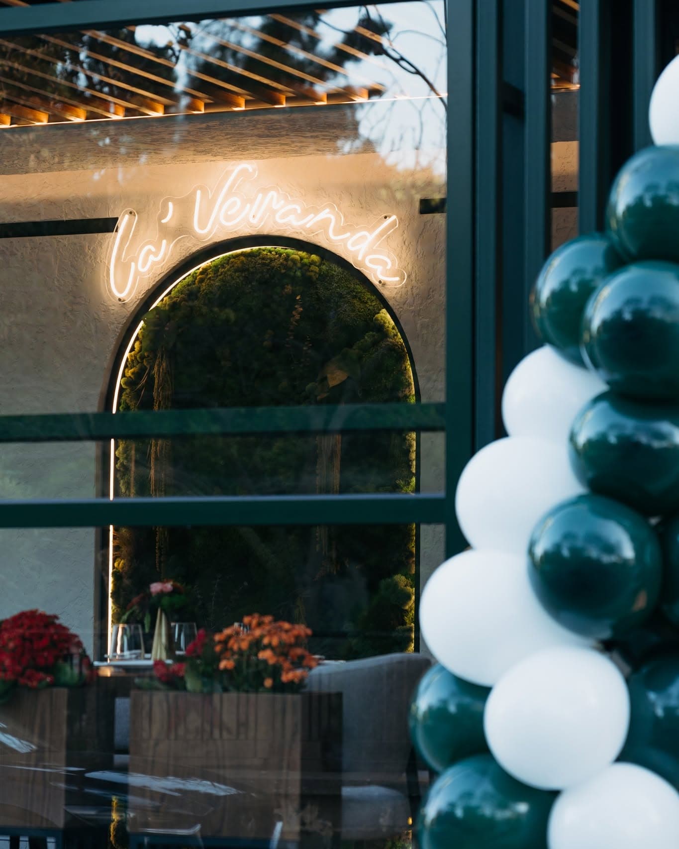 Sun-lit veranda terrace with greenery, wooden tables and warm seating at La' Veranda